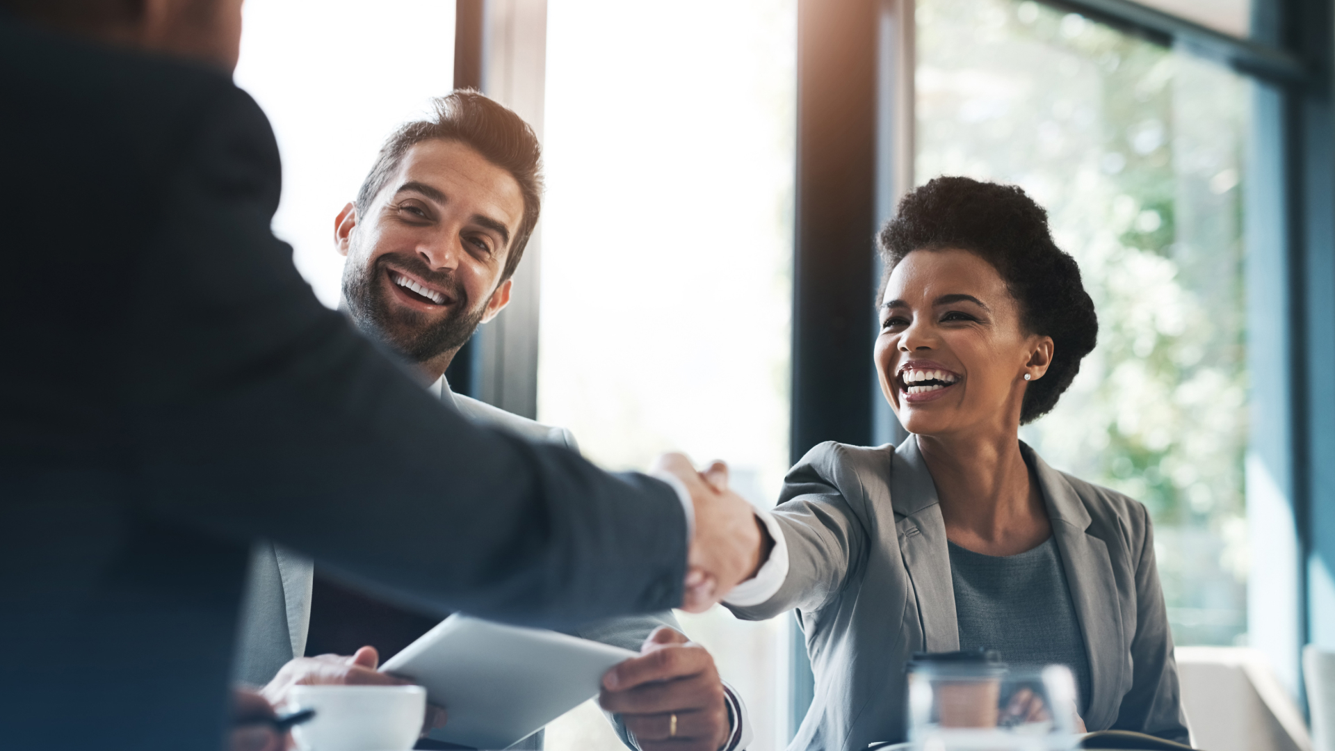 Equipe de clientes sorridentes apertando a mão de consultor da Fenicio após conclusão de treinamento corporativo de alta performance.