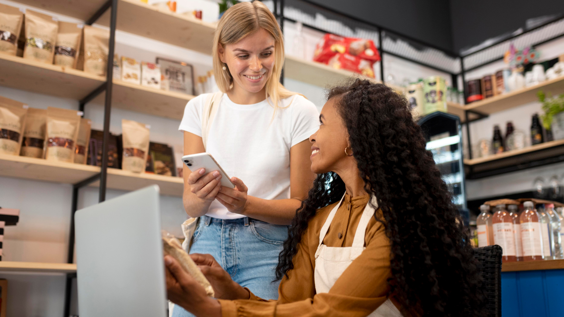 Consultora da Fenicio auxiliando proprietária de loja de produtos naturais com integração de sistemas e atendimento via smartphone e notebook.