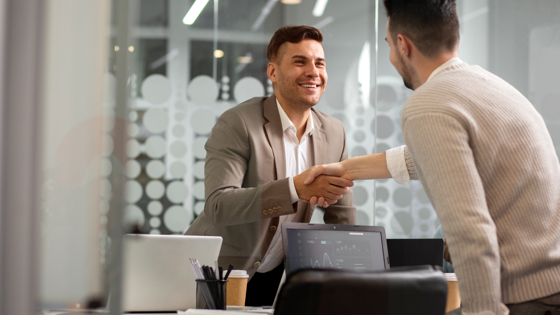Consultor da Fenicio apertando a mão de parceiro comercial em escritório moderno, celebrando o sucesso do treinamento e alinhamento estratégico.