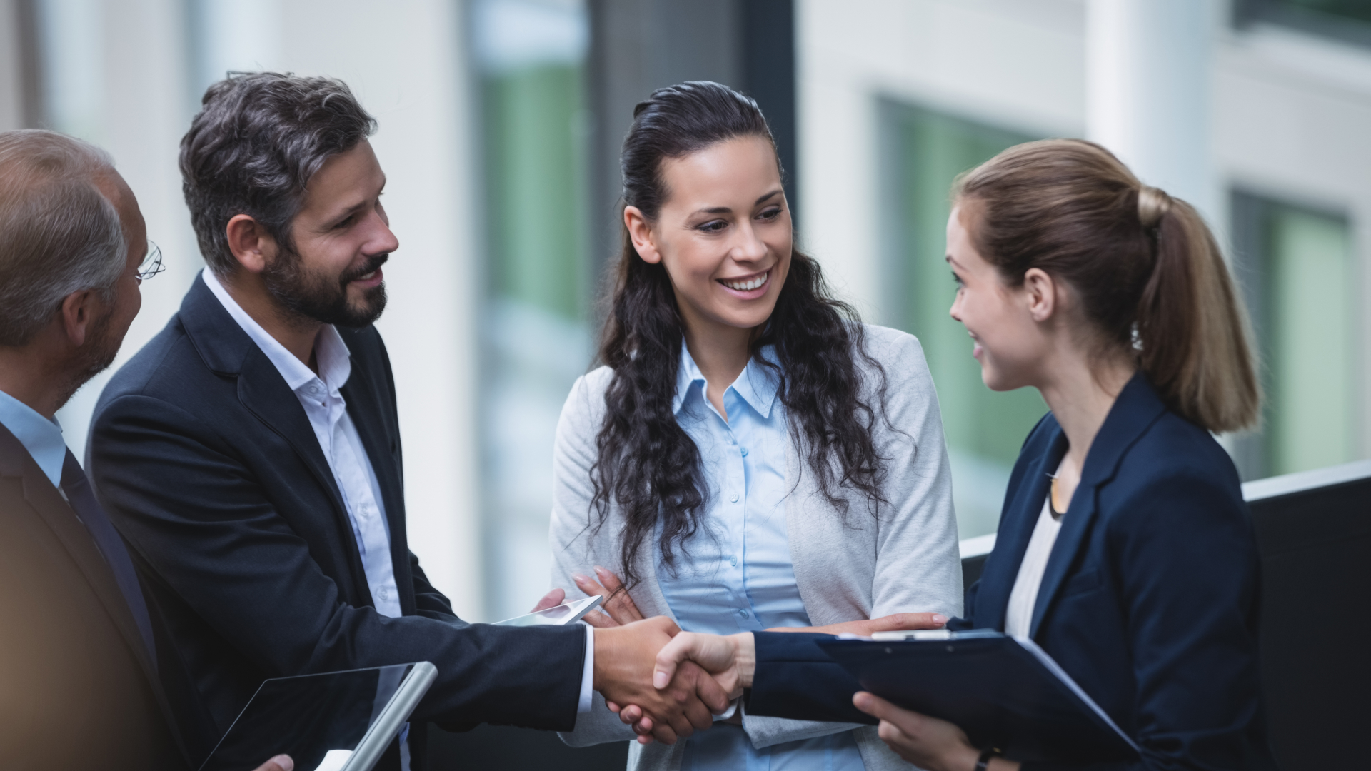 Executivos sorridentes apertando a mão de consultor da Fenicio após treinamento de liderança corporativa bem-sucedido.