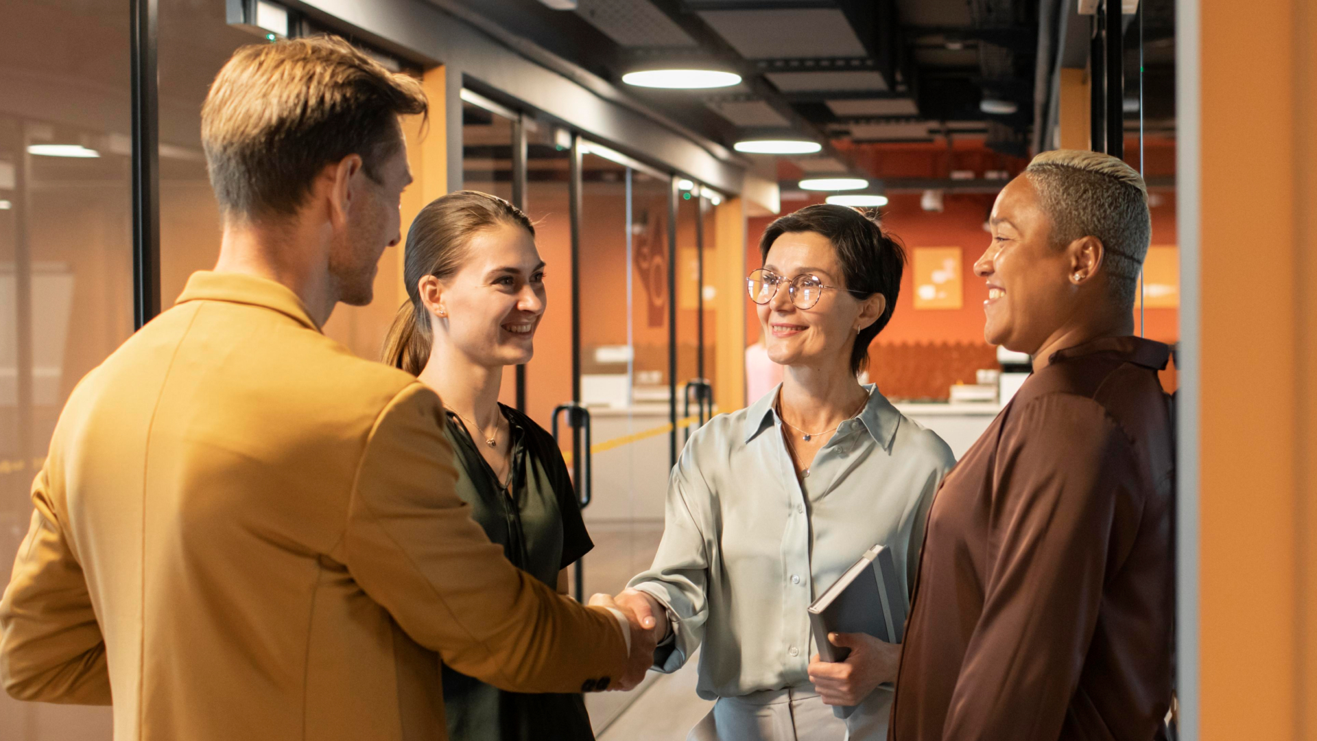Consultor da Fenicio apertando a mão de gestora após treinamento de equipe bem-sucedido em escritório moderno.