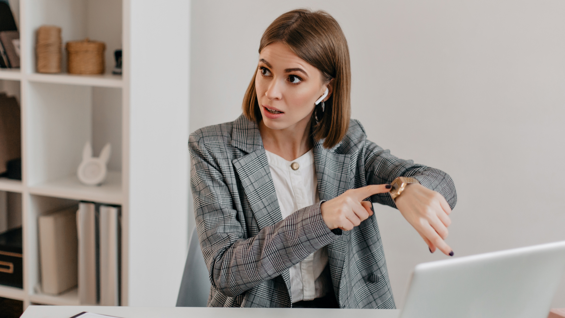 Executiva apontando para o relógio durante reunião online, ilustrando a urgência em treinamentos de gestão de tempo e produtividade da Fenicio.