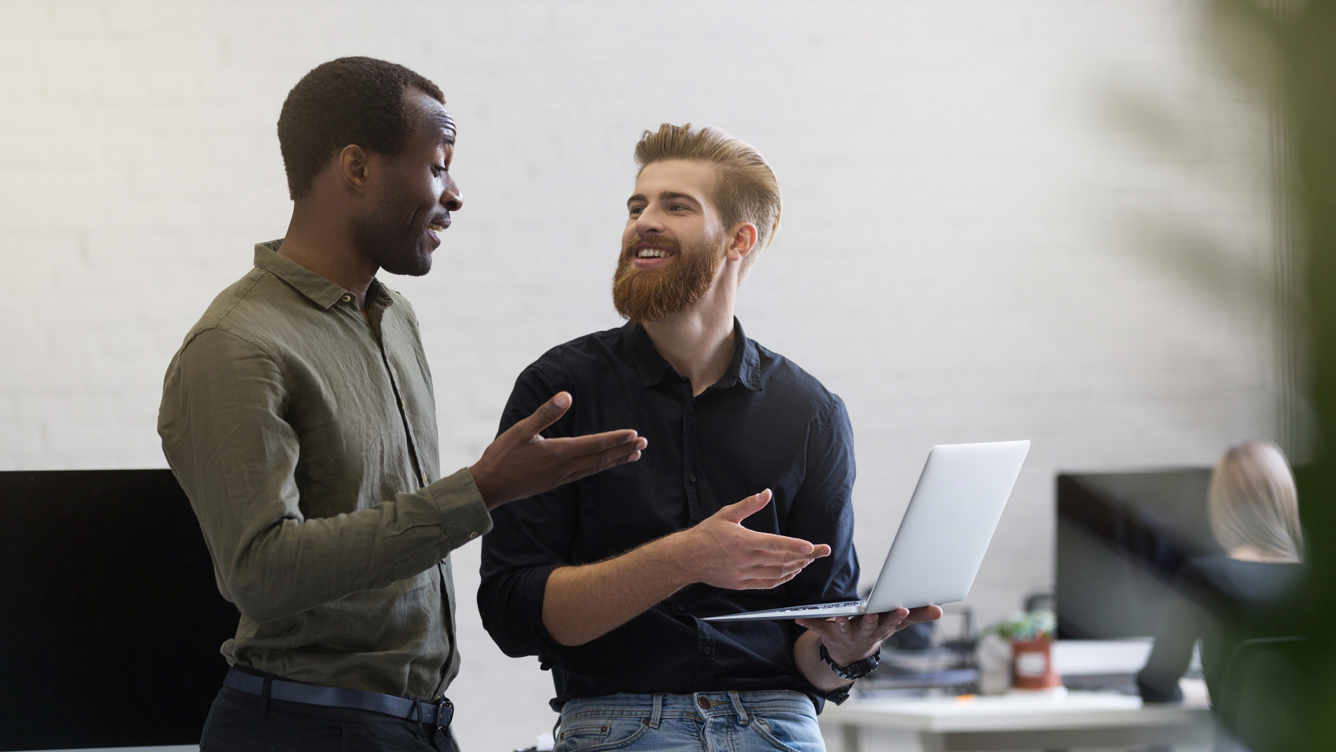 Consultores da Fenicio em conversa técnica sobre projeto digital, utilizando notebook em ambiente de coworking moderno.